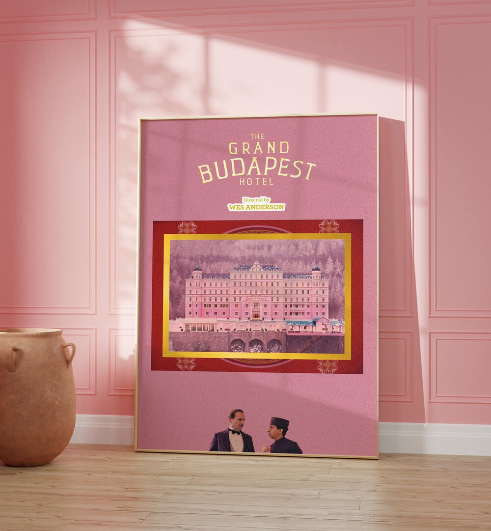 Grand Budapest Hotel By Grishma Korjani Movie Posters in Oak Wood Plain Frame placed on a Wooden Floor near a Pink Colored Wall