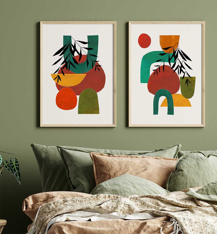Two abstract art prints on a wall above a sofa with pillows.