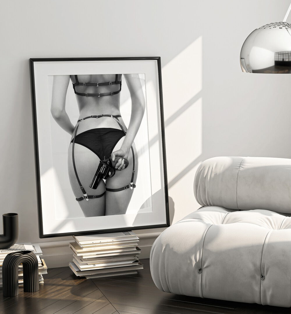 Gun by David Drake Fine Art Photography Fashion Photography in Black Frame With Mount placed on a stack of books beside a  sofa