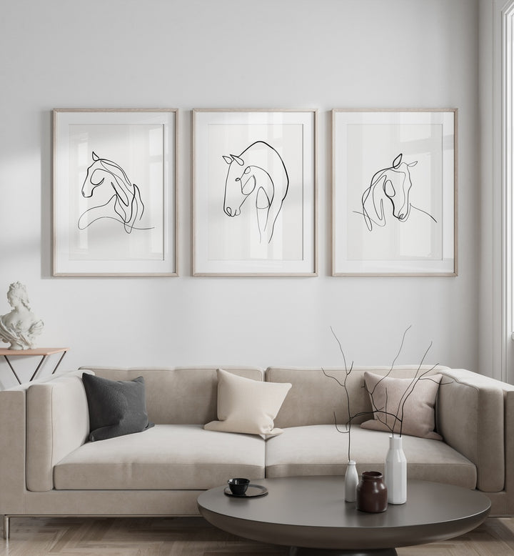 Horses Line Art Set Set Of 3 Paintings in White Frame With Mount placed on the white wall behind a sofa