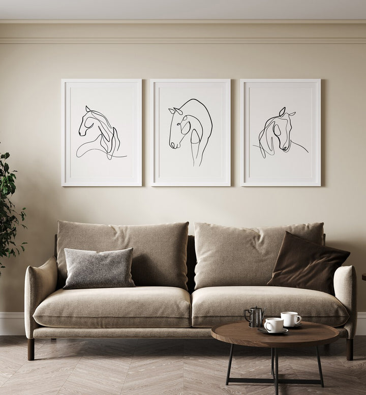 Horses Line Art Set Set Of 3 Paintings in White Frame With Mount placed on the beige wall behind a brown sofa