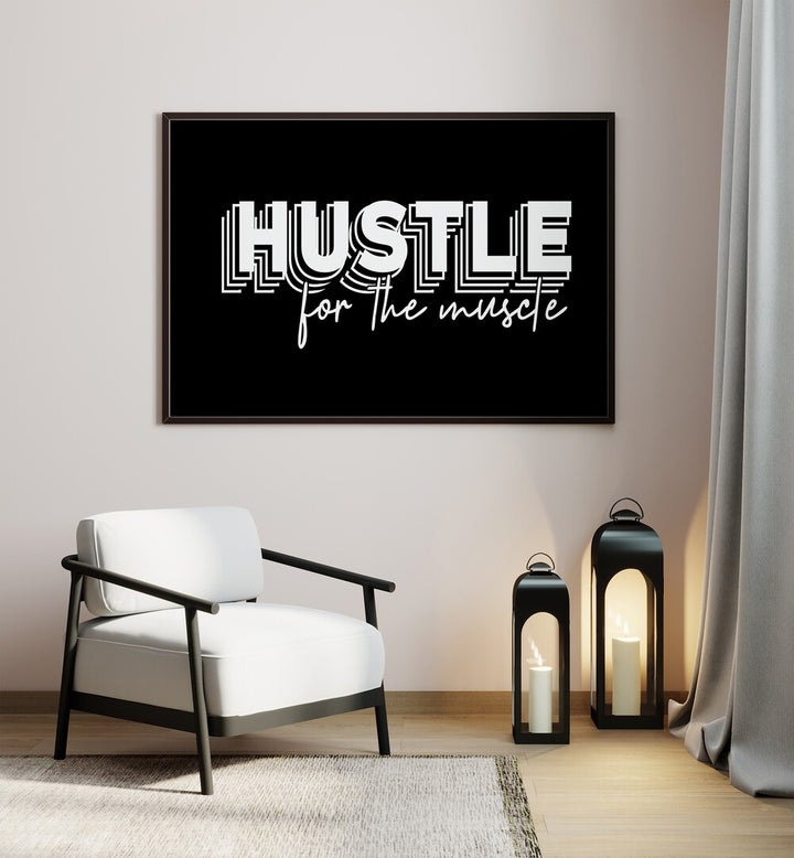 Hustle for the Muscle Quotes and Typography Posters in Black Plain Frame placed on a wall beside a chair