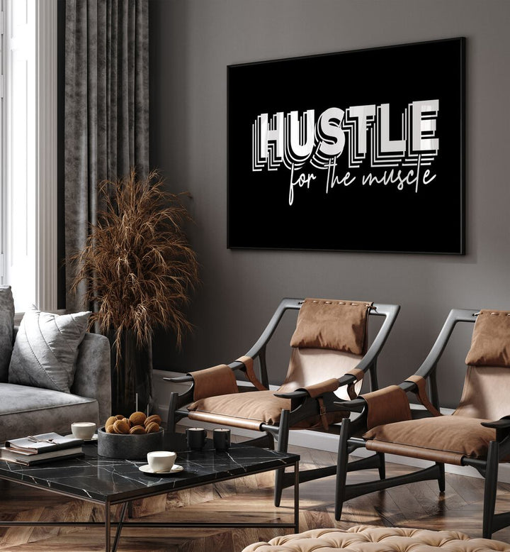 Hustle for the Muscle Quotes and Typography Posters in Black Plain Frame place on a wall in living room behind a chair