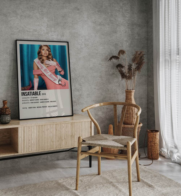 INSATIABLE 2018 MOVIE POSTERS in Black Plain Frame placed on a table beside chair
