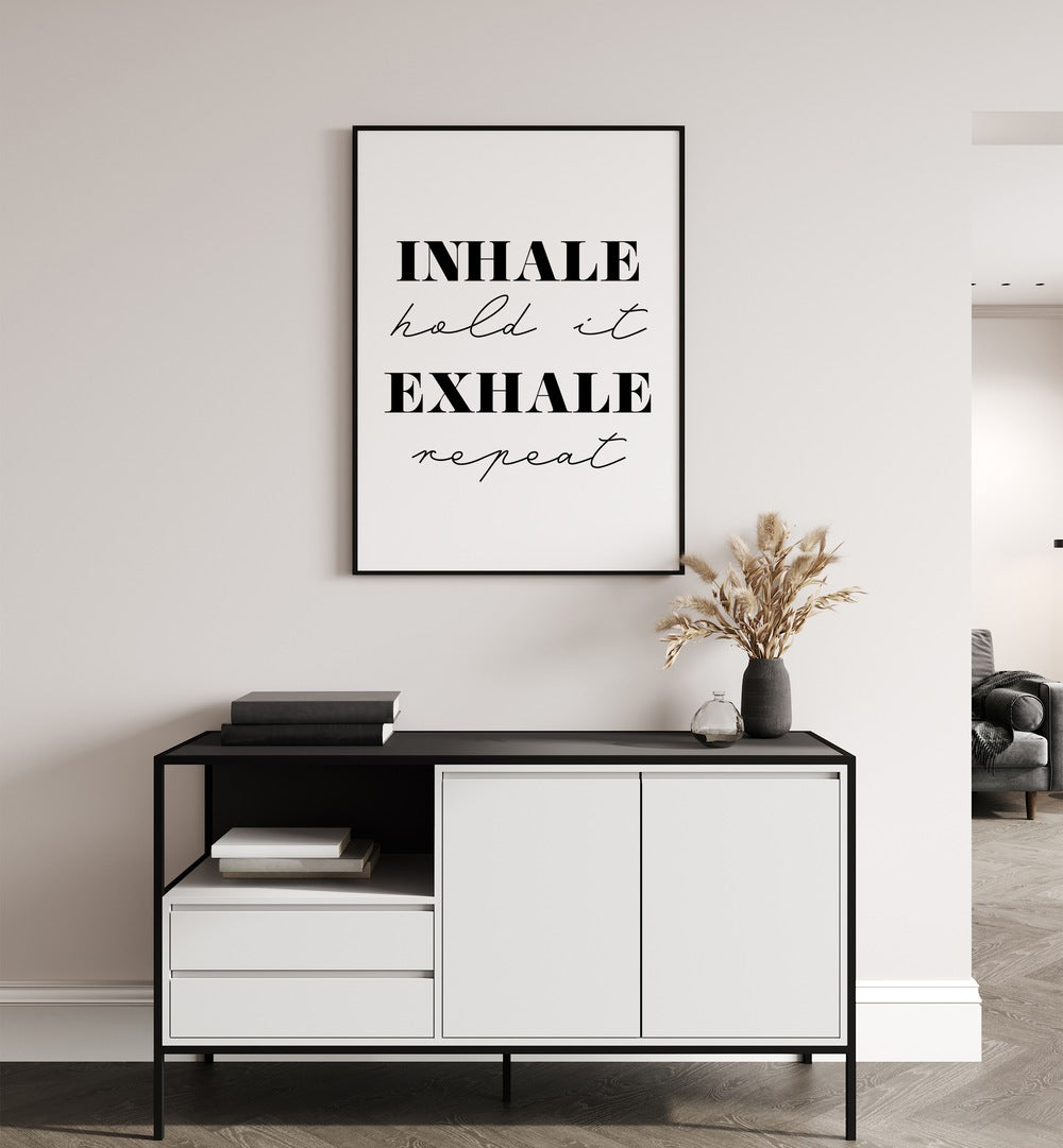 Inhale And Exhale By 1 X Studio Quotes And Typography Posters in Black Plain Frame placed on a White Colored Wall above a Console Table in the Drawing Room