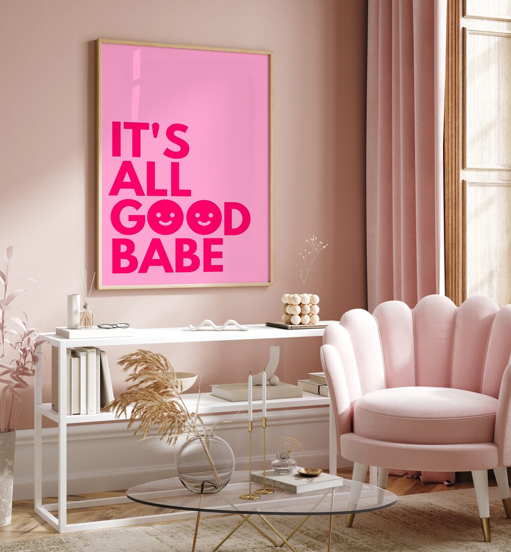 Its All Good Babe by Athene Fritsch Quotes and Typography Posters in Oak Wood Plain Frame placed on a pink wall beside a window and behind a table