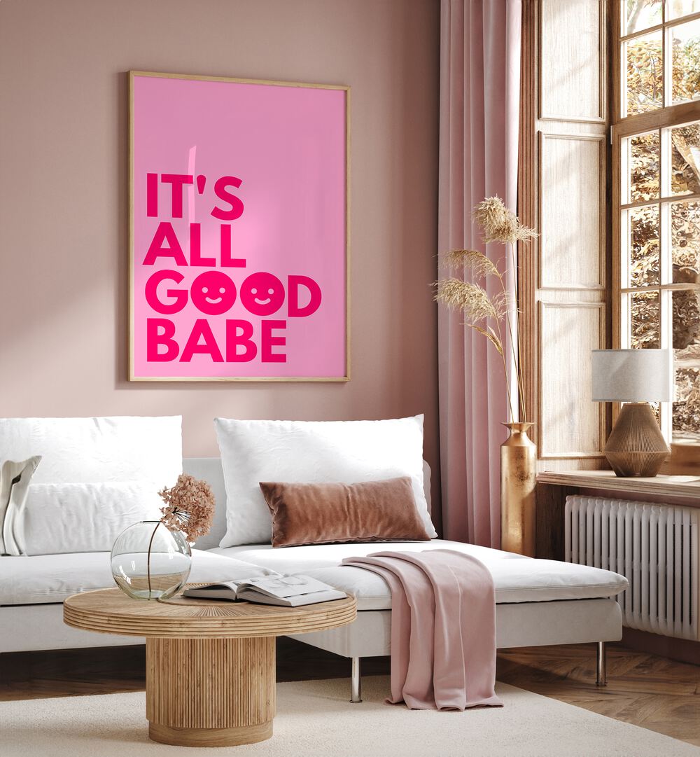 Its All Good Babe by Athene Fritsch Quotes and Typography Posters in Oak Wood Plain Frame placed on a pink wall beside a window and behind a sofa for living room