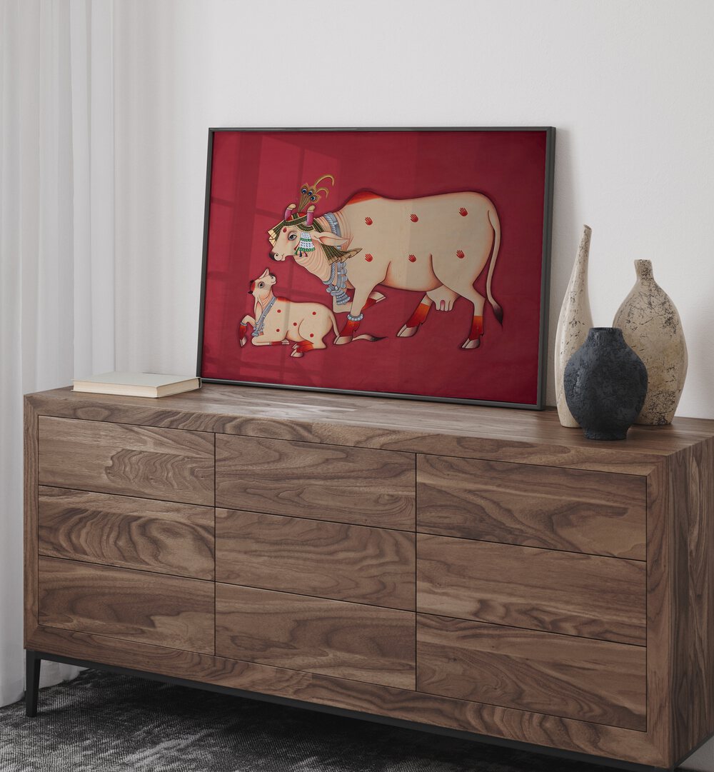 Kamdhenu Cow And Calf Indian Art Painting Artwork in Black Plain Frame placed on a Wooden Console Table  next to a Cream Beige Wall