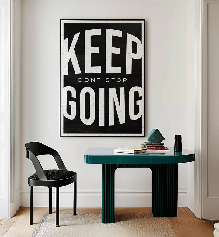 Keep Going Dont Stop Quotes And Typography Posters in Black Plain Frame placed on a Cream Colored Wall near a Study Table in a Workspace in the Drawing Room