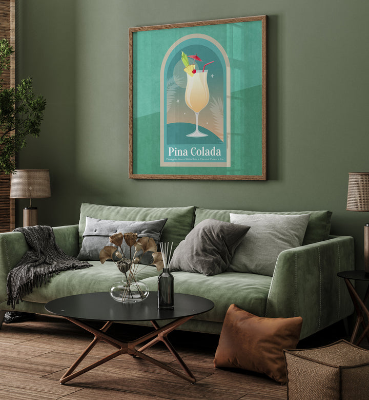 Kokteyl Pina Colada By Emel Tunaboylu Bar Posters Bar Art Prints in Oak Wood Plain Frame placed on a Green Colored Wall near a Green Sofa in the Living Room