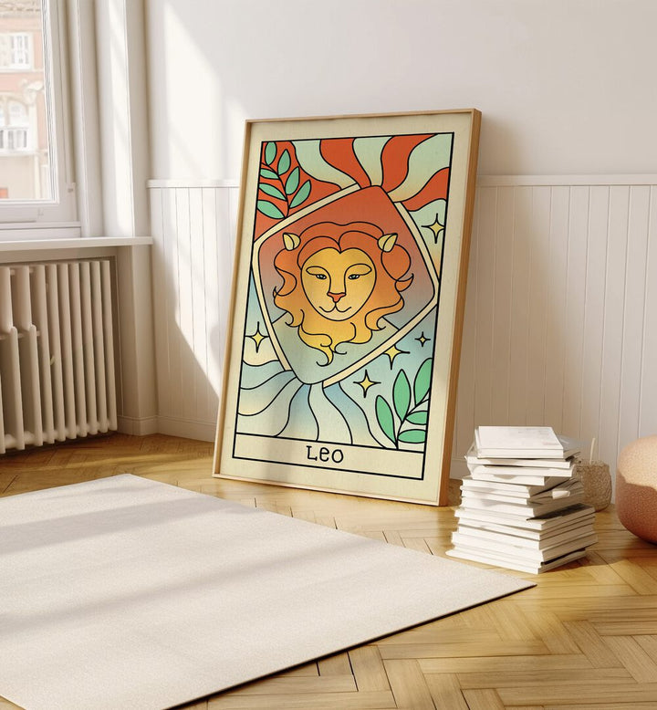 Leo Zodiac & Tarot Art Painting Artwork in plain oakwood frame on a wooden floor beside a stack of books