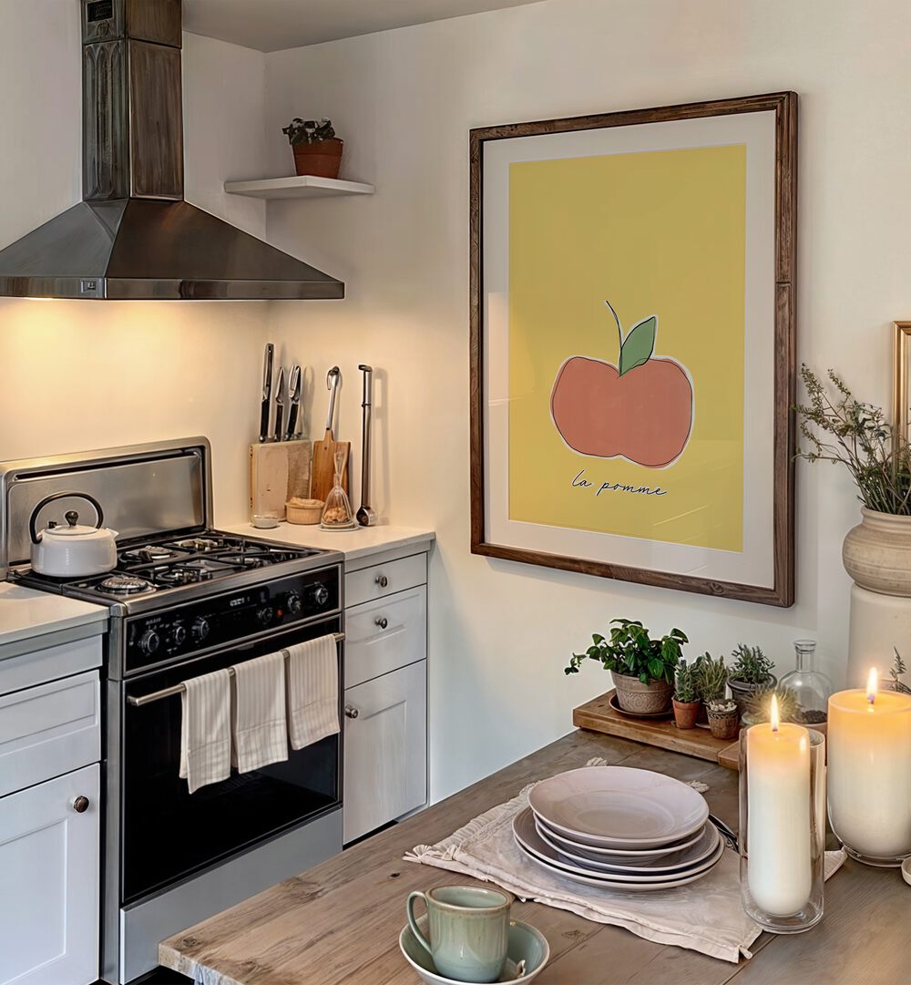 La Pomme by Uplus Me Studio Kitchen Art Prints Kitchen Posters in Dark Wood Frame With Mount placed on wall in kitchen area between a table and stove