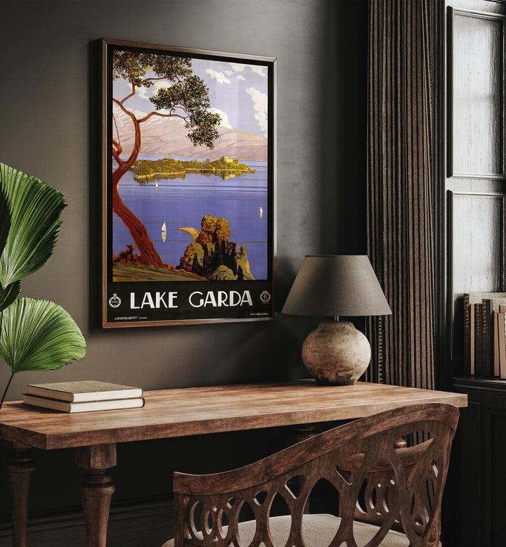 Lake Garda Retro Vintage Travel Vintage Travel Posters in Dark  Wood Plain Frame on a wall above a study table beside a plant