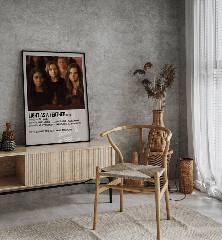 Light As Feather 2018 Movie Posters in Black Plain Frame placed on a table beside oakwood chair
