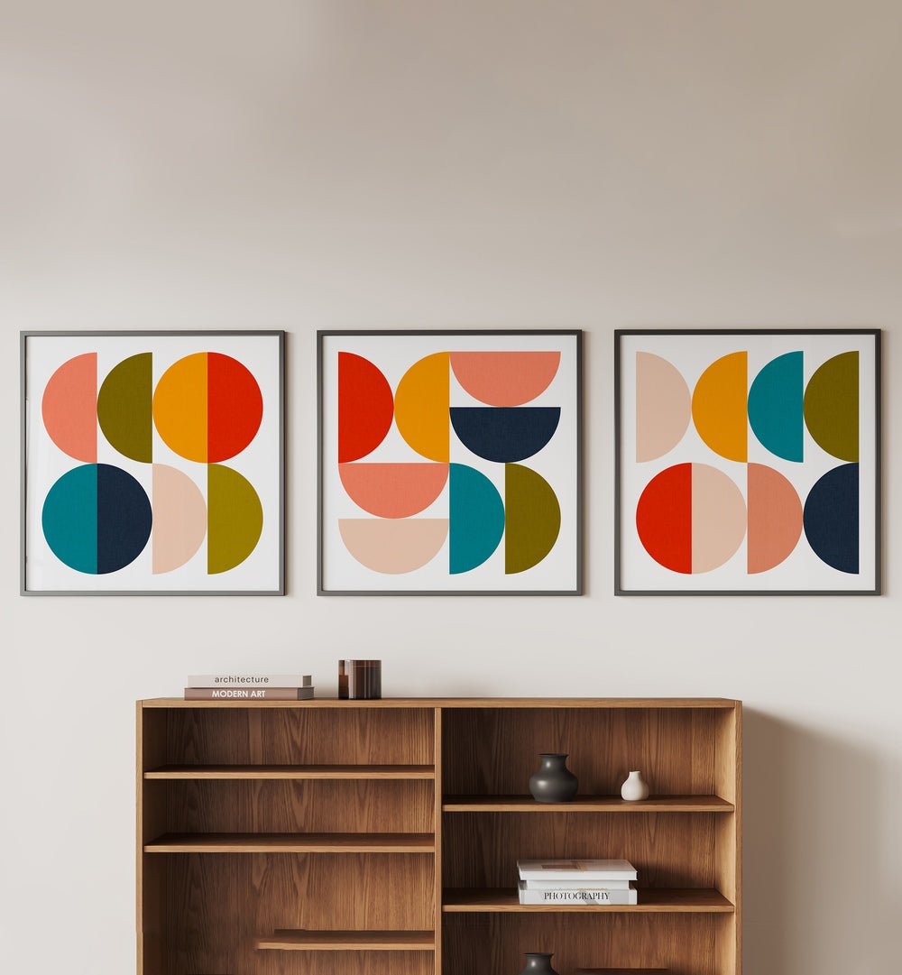 Mid-Century Geometrical Colour Play Set Of 3 Paintings in Black Plain Frame placed on a wall behind a brown table