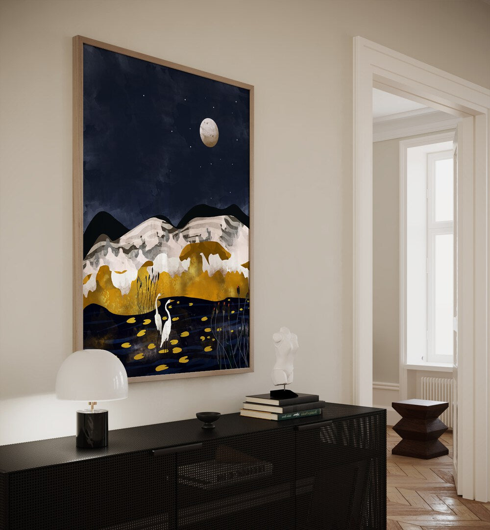 Midniight Lake By Uma Gokhale Landscape Art Prints in Oakwood Plain Frame on a white wall above a black table