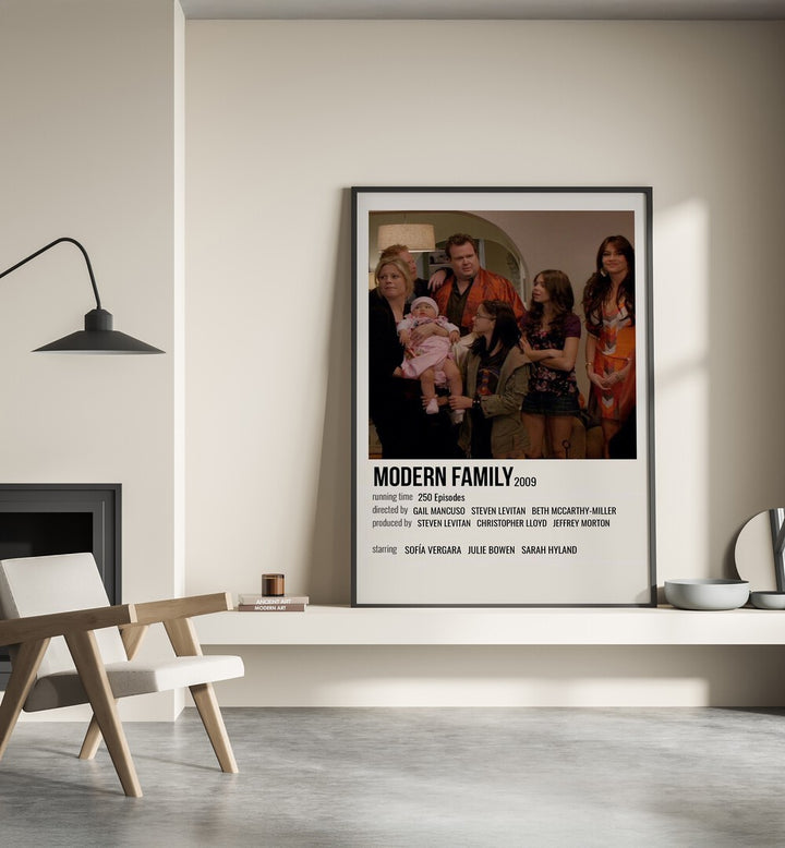 Modern Family 2009 Movie Posters in Black Plain Frame place on a wall behind a chair beside lamp