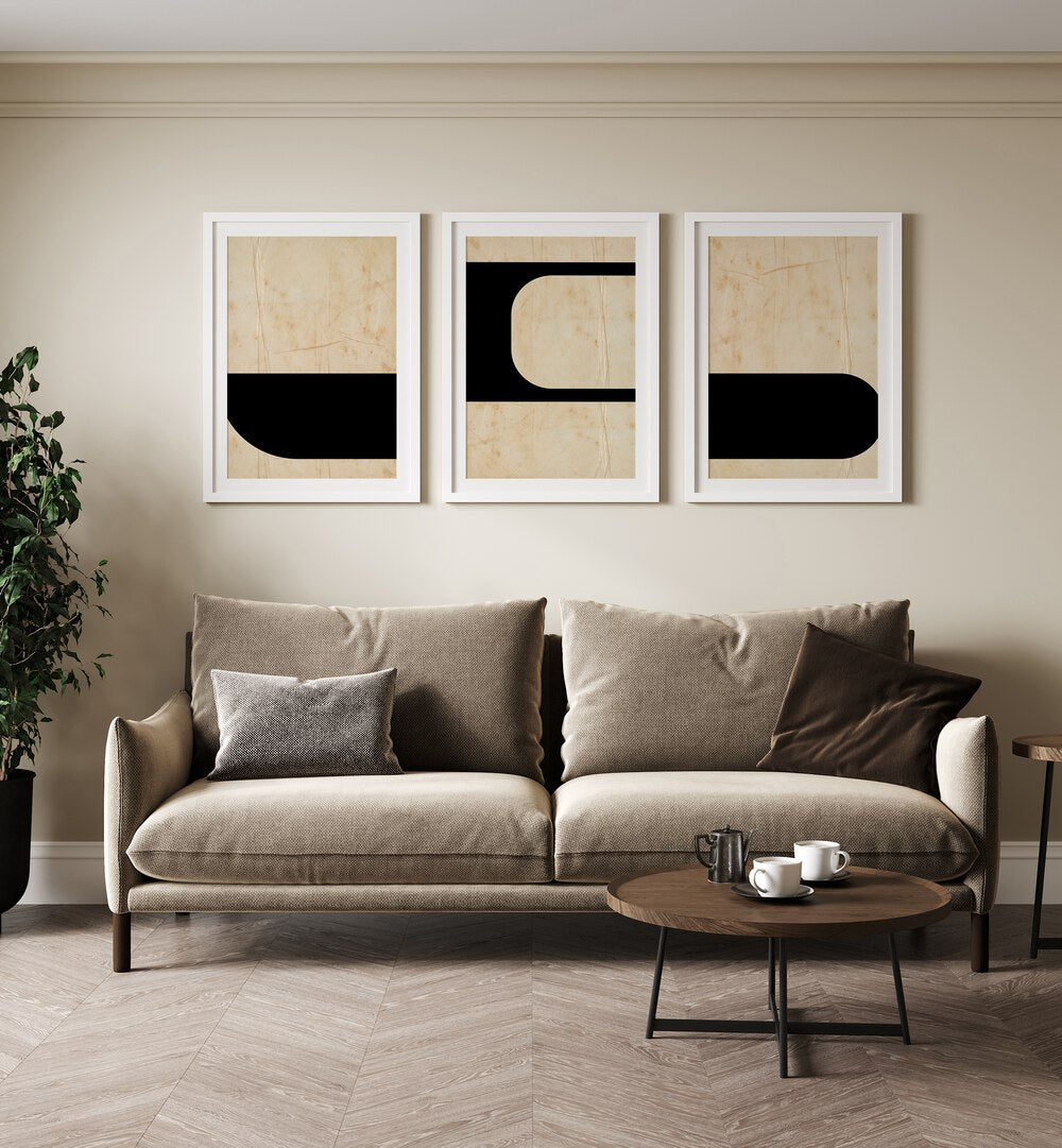 Modern Geometric Set Set Of 3 Paintings in White Frame With Mount placed on a beige wall behind a sofa and beside a plant