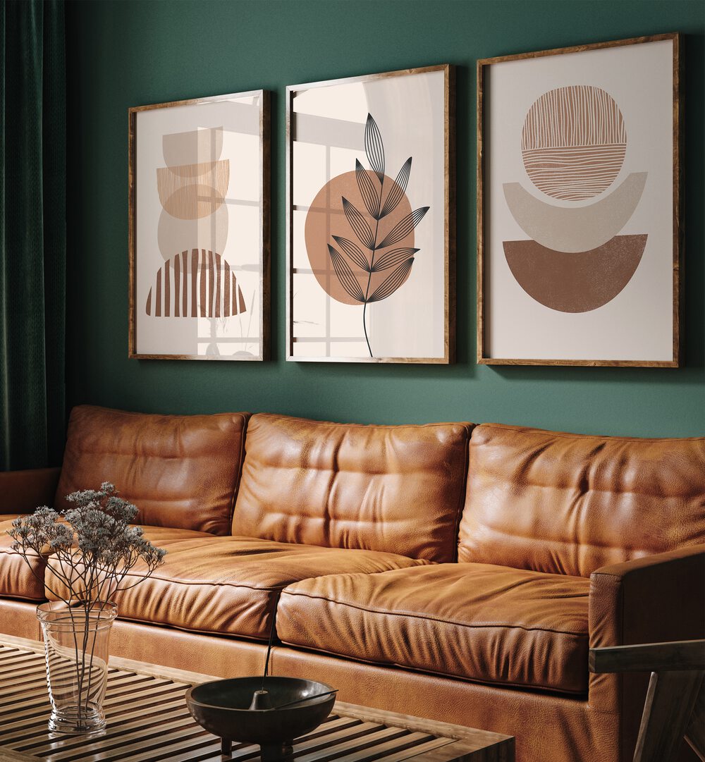 Modern Leaf Geometric Set Set Of 3 Paintings in Dark Wood Plain Frame placed on a living room wall behind a leather sofa