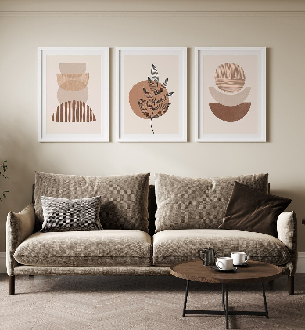 Modern Leaf Geometric Set Set Of 3 Paintings in White Frame With Mount placed on a living room wall behind a sofa