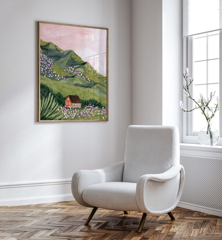 Mountain House By Sarah Gesek Landscape Art Prints in Oak Wood Plain Frame placed on a white wall beside a white chair and a window