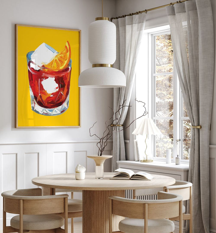 Negroni on Sunshine by Alice Straker Bar Posters Bar Art Prints in Oak Wood Plain Frame placed on a wall in a dining room area beside a window and behind a dining table