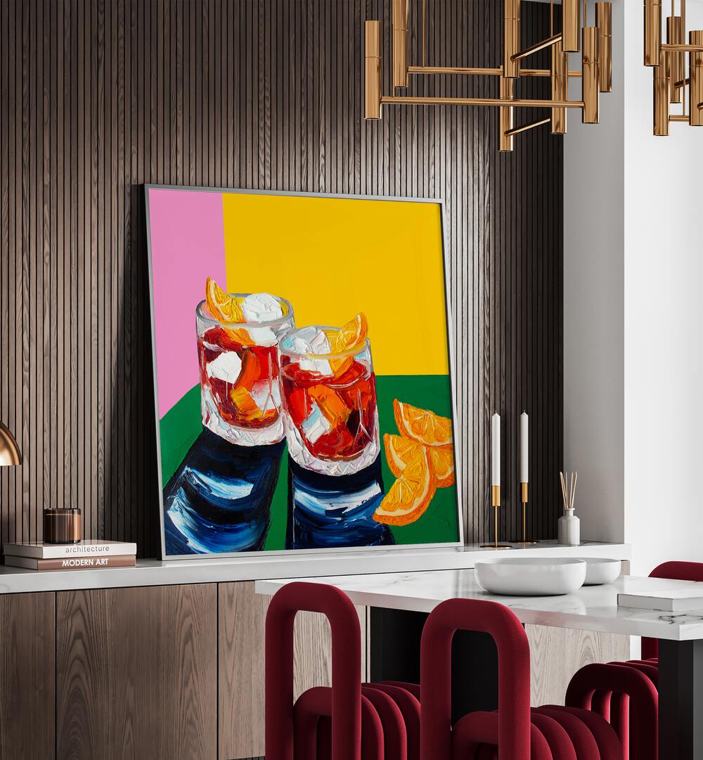 Negronis I by Alice Straker Kitchen Posters Kitchen Art Prints in Black Plain Frame placed on a console table behind a dining table for dining area