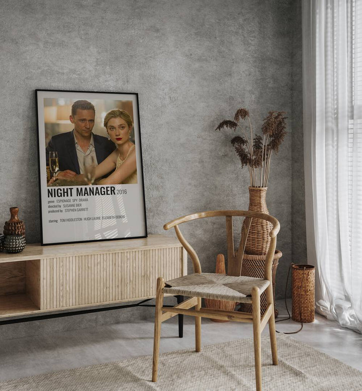 Night Manager 2016 Movie Posters in Black Plain Frame placed on a table beside oakwood chair