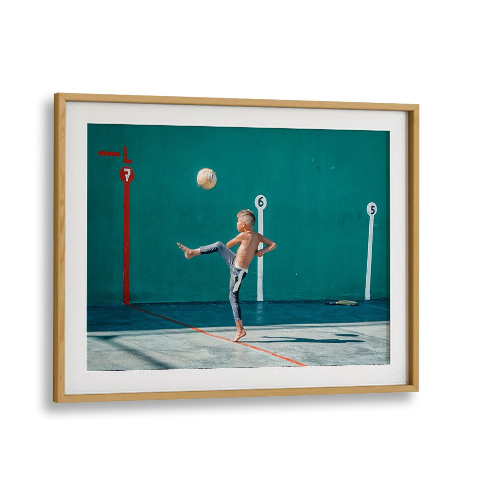 A child skillfully kicks a yellow ball in vibrant street photography prints, capturing urban life’s essence.