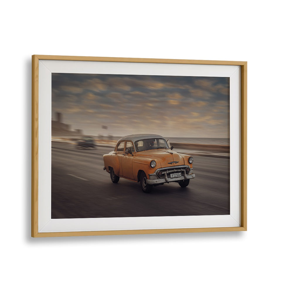 Capture the essence of urban life with MALECON VII, PHOTOGRAPHY PRINTS featuring a classic orange car in motion.
