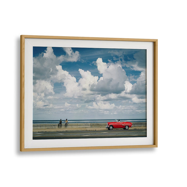 Captivating urban scene featuring a classic car and figures by the sea, showcasing MALECON VIII, PHOTOGRAPHY PRINTS.