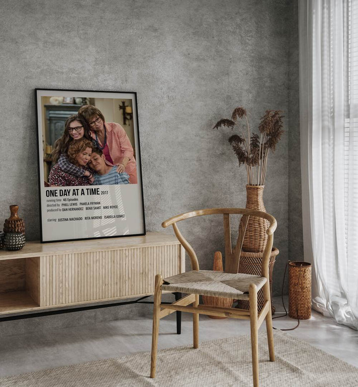 One Day At A Time 2017 Movie Posters in Black Plain Frame placed on a table beside oakwood chair