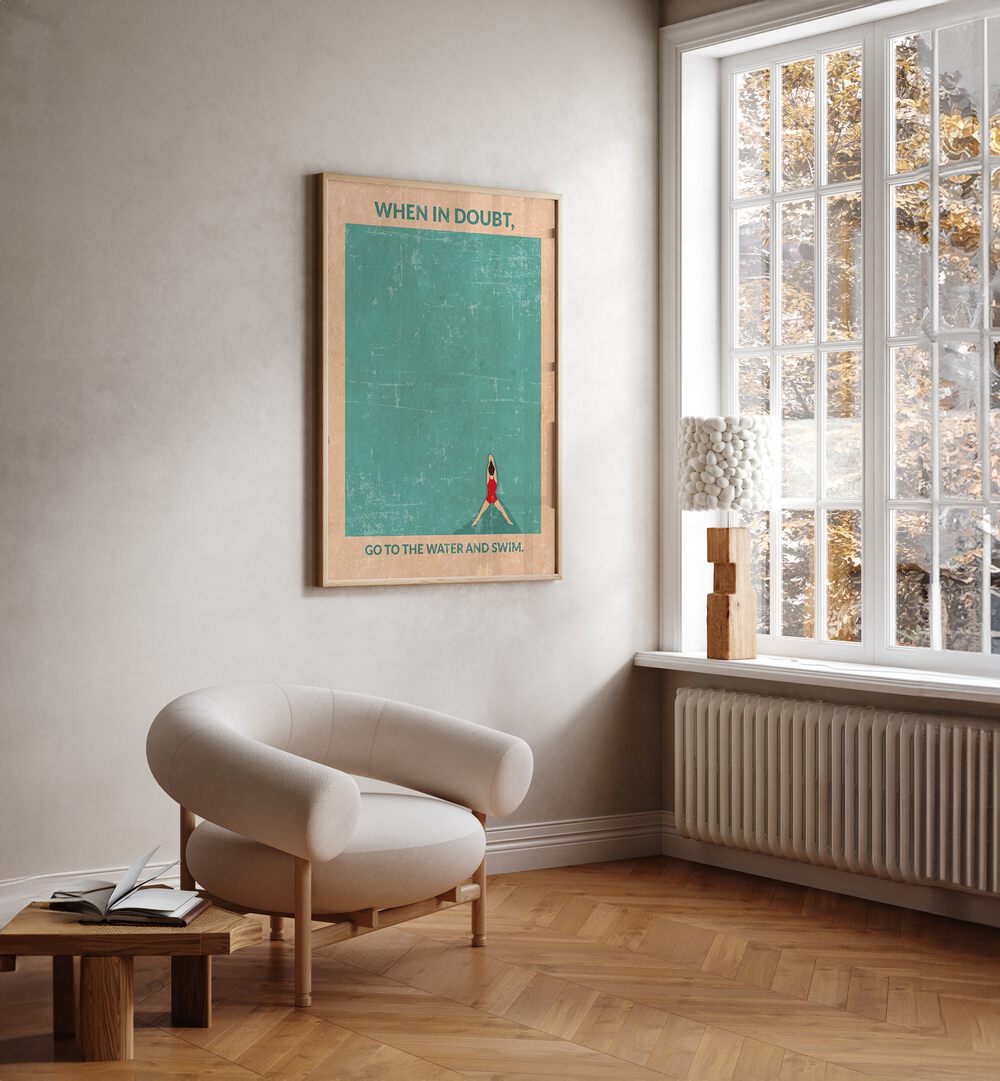 Open Water Standard Wall Art Sports Posters in Oak Wood Plain Frame placed on a white wall beside a white chair and a window