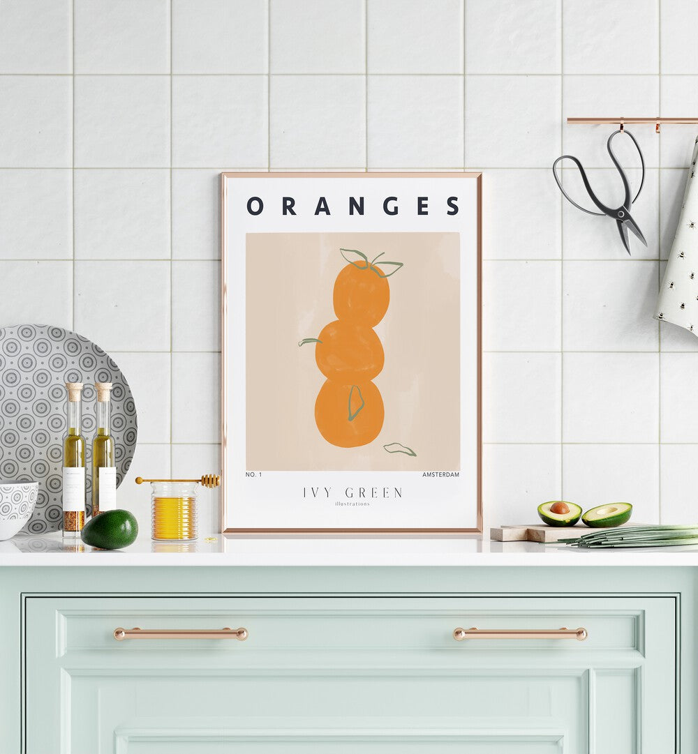 Oranges By Ivy Green Kitchen Art Prints in Oak Wood Plain Frame on a kitchen counter beside avocados for kitchen area