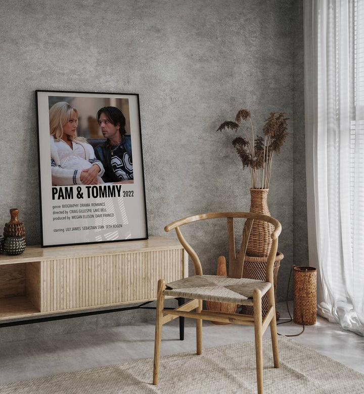 Pam Tommy 2022 Movie Posters in Black Plain Frame placed on a table beside oakwood chair