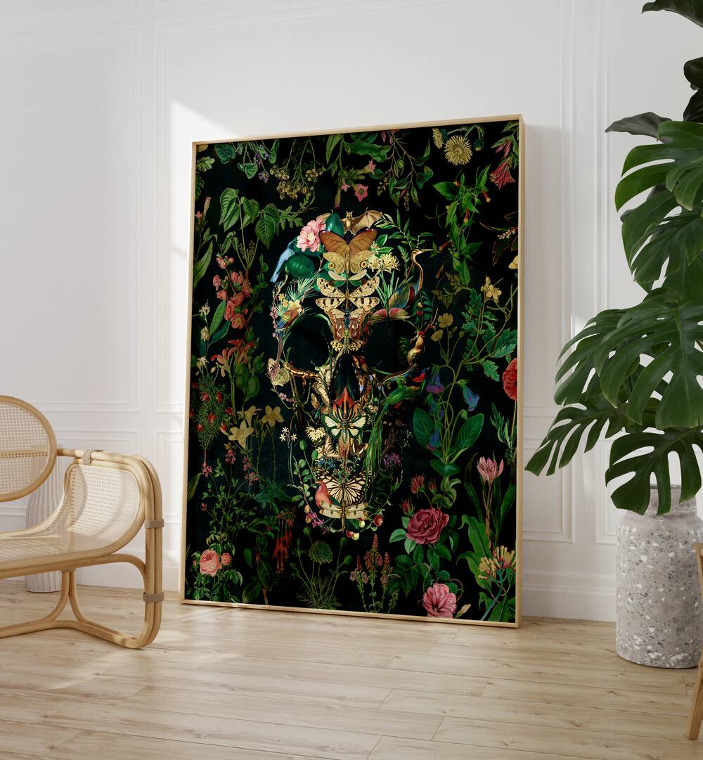 Papillon Skull Botanical Art Prints Floral Paintings in Oak Wood Plain Frame placed on the floor between a chair and a plant