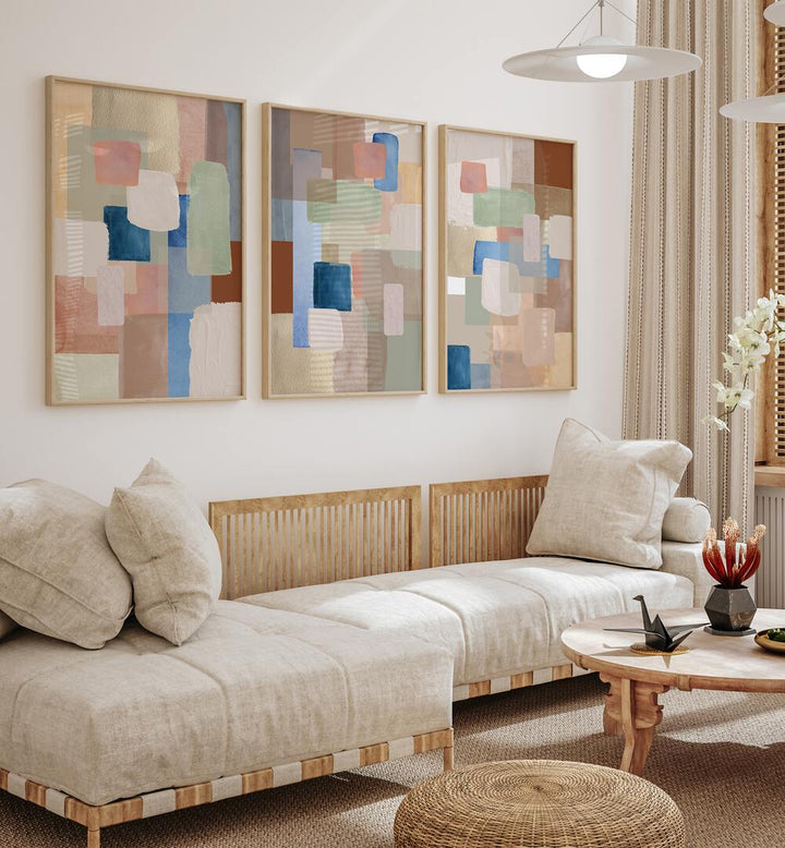 Pastel Color Abstract Set Of 3 Paintings in Oak Wood Plain Frame placed on a wall living room wall behind a sofa