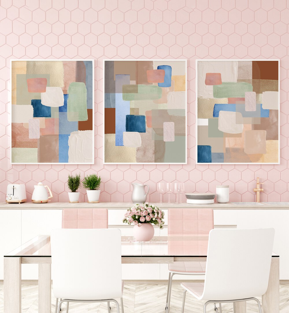 Pastel Color Abstract Set Of 3 Paintings in White Plain Frame placed on a wall behind a kitchen counter and dining table