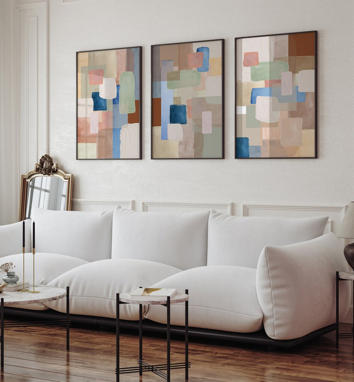 Pastel Color Abstract Set Of 3 Paintings in Black Plain Frame placed on a wall living room wall behind a sofa