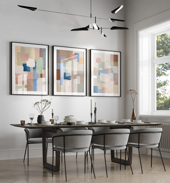 Pastel Color Abstract Set Of 3 Paintings in Black Frame With Mount placed on a wall behind a dining table and beside a window for dining area