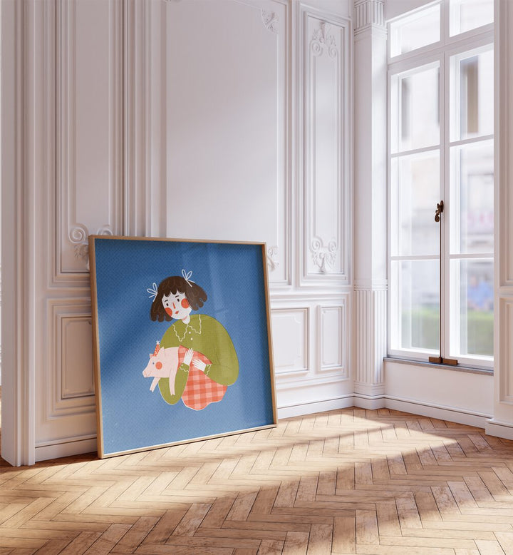 Piggie in the Blanket By Julia Leister Kids Room Art in Oak Wood Plain Frame placed on a wooden floor beside a window