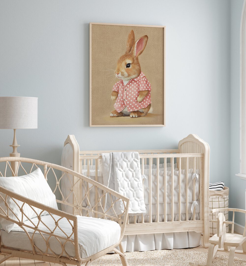 Pink Perfection Bunnys Style Kids Room Paintings Kids Room Wall Art in Oak Wood Plain Frame placed on a wall in a kids room behind an infant's bed