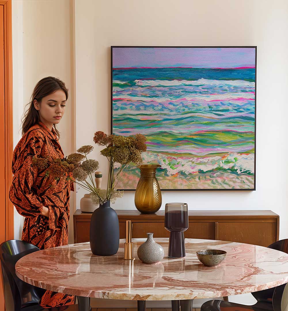 PINK SEAS , BEACH PAINTINGS pastel seascape on wall above sideboard with dried vases and woman beside marble dining table