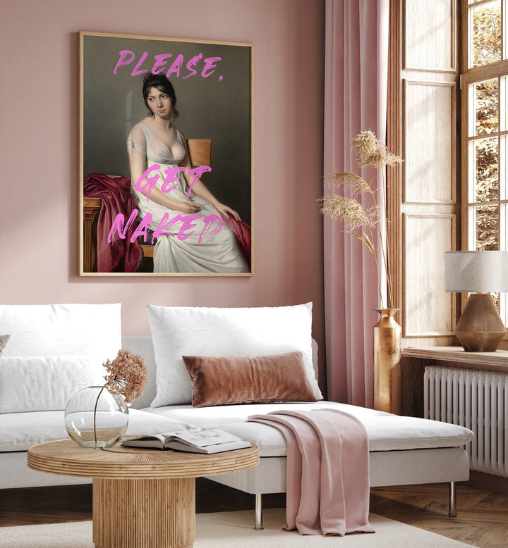 Please Get Naked by the Art Concept Altered Art Prints in Oak Wood Plain Frame placed on a wall behind a white sofa