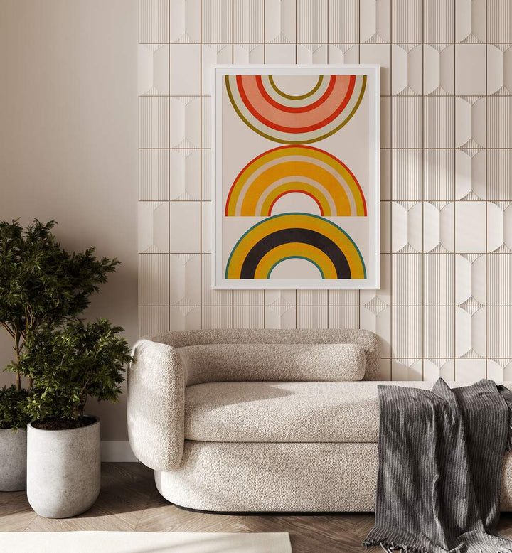 Rainbow Suns Vi By Ana Rut Bre Abstract Art Abstract Wall Art in White Frame With Mount placed on a wall behind a sofa