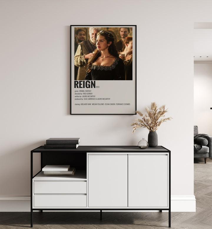 Reign Movie Posters in Black Plain Frame placed on a white wall behind a black and white table