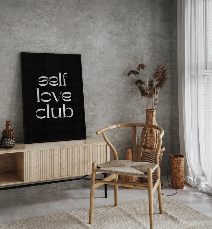 Self Love Club by Anne-marie Volfova Quotes and Typography Posters in Black Plain Frame placed on a console table behind a chair, beside a window