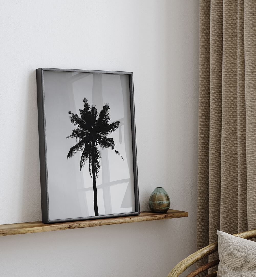 Shadowed Tropics Beach Prints Coastal Wall Art in Black Plain Frame placed on a Shelf near a White Colored Wall 