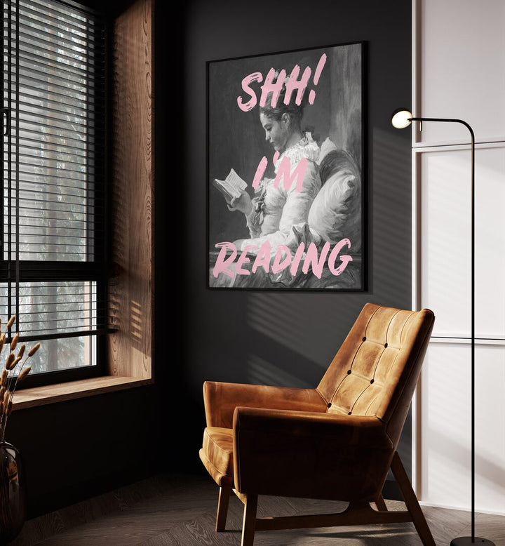 Shh Im Reading By Grace Digital Art Co Altered Art Prints in Black Plain Frame placed on a wall beside an orange sofa and a window