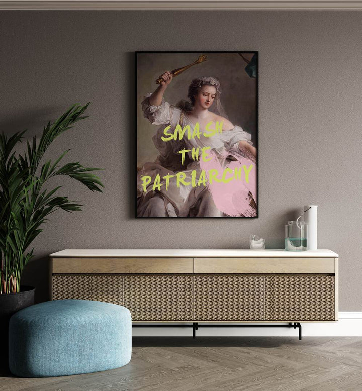 Smash the Patriarchy By Grace Digital Art Co Altered Art Prints in Black Plain Frame placed on a wall behind a console table and a plant